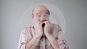 Senior man biting on his fingernails with a worried expression