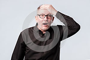 Senior man in black shirt putting his hand on the forehead remembering something photo