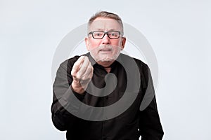 Senior man in black shirt showing italian gesture that means what do you want