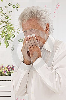 Senior man blowing his nose