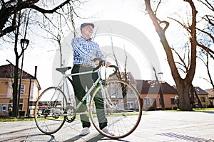 Senior man in blue checked shirt with bicycle in town.