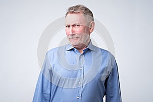 Senior man in blue shirt looking with disbelief expression .