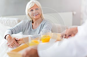 Senior man bringing his wife breakfast in bed