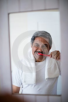 Senior man brushing teeth in bathroom