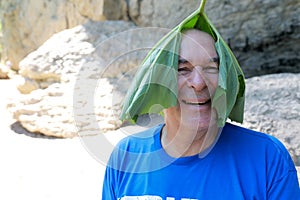 Senior man with burdock leaf on his head