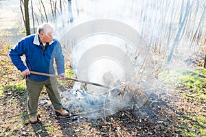 Senior man is burning dry branches.