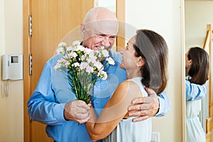 Senior man came to mature woman with flowers