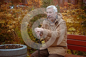 an senior man with a cane sits on a bench in an autumn park, dementia and alzheimer's disease