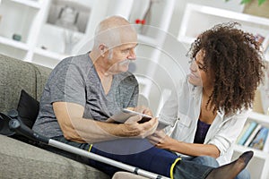 Senior man and carer using tablet on sofa