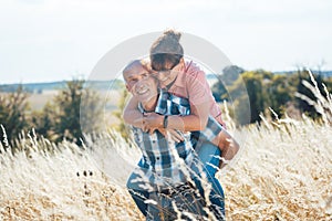 Senior man carrying his wife piggyback on his back