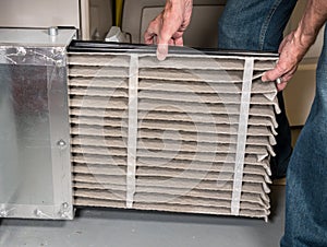 Senior man changing a dirty air filter in a HVAC Furnace