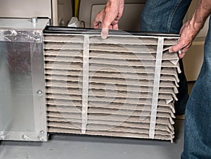 Senior man changing a dirty air filter in a HVAC Furnace photo