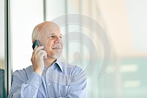 Senior man chatting on his smartphone in a high key portrait