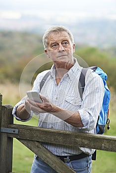 Senior Man Checking Location With Mobile Phone On Hike