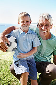 Senior man, child and football happy in portrait outdoor on field for training, exercise or development. Grandpa