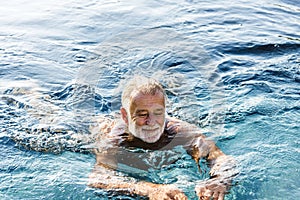 Senior man chilling in swimming pool photo