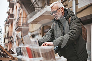 Senior man chooses vintage vinyl records at a flea market. Buys rare audio recordings, nostalgia