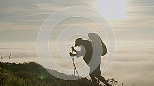 Senior man climbing mountain with trekking sticks at sunset
