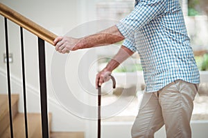 Senior man climbing upstairs with walking stick