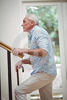 Senior man climbing upstairs with walking stick