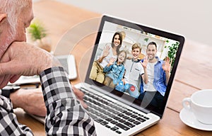 Senior man communicating to his family online, speaking to his nears on webcam