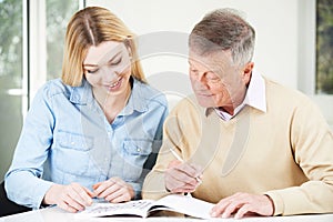 Senior Man Completing Crossword Puzzle With Teenage Granddaughter Daughter