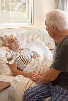 Senior man consoling of his sick wife in bed