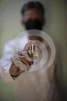 Senior man with corona preventive mask holding medicine ampul in his hand.