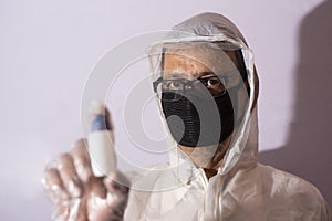 Senior man with corona preventive mask and PPE suit showing ampul in front of a white copy space background.