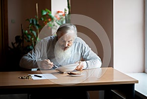 Senior  man counting money and plans to buy grocery while sitting at an empty soup plate