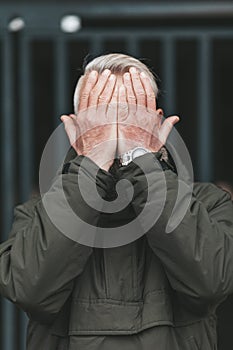 The senior man covered his face with his hands. Age crisis, depression in people. Adult mistakes and despair