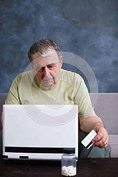 Senior man with credit card paying bills at laptop