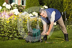 Senior man crimping hose in the garden