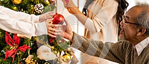 Senior man decorate christmas tree with family