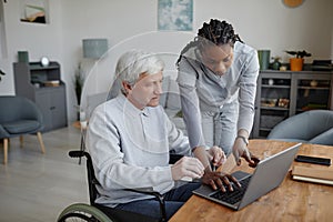 Senior man with disability learning to use computer with nurse