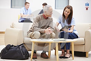 Senior Man Discussing Results With Nurse On Digital Tablet