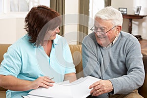 Senior Man In Discussion With Health Visitor At Ho