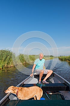 Senior man with dog in motor boat