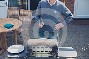 Senior man doing barbecue in garden