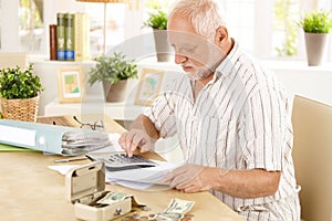 Senior man doing calculation at home photo