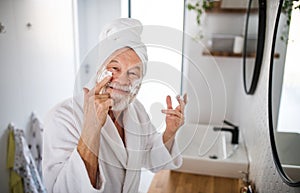 A senior man doing morning routine in bathroom indoors at home.