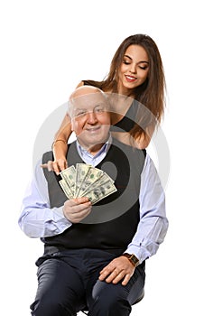 Senior man with dollar banknotes and young woman on white background. Marriage of convenience
