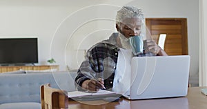 Senior man drinking coffee while taking notes
