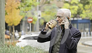 Senior man drinking coffee and talking on phone outdoors