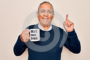Senior man drinking cup of coffee with best dad ever message over white background surprised with an idea or question pointing