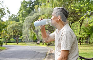 senior man drinking water after workout in the park for body refreshment