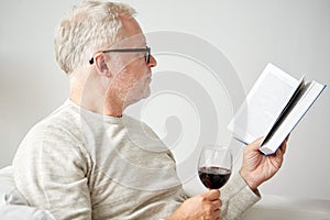 Senior man drinking wine and reading book