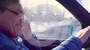 Senior man driving car and talking by mobile phone