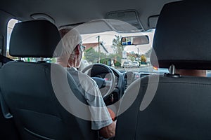 Senior man driving car, wide angle interior view