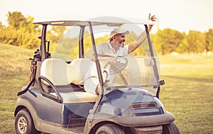 Senior man driving golf car